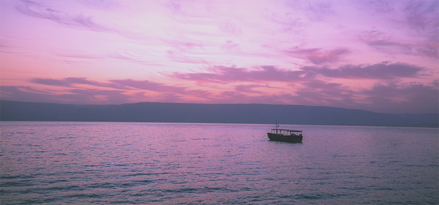 Boat seems at peace in the middle of the Sea of Galilee at sunset 